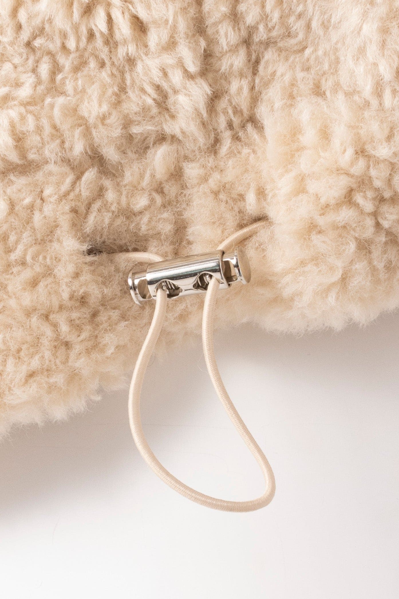 Close up image of the elasticated feature on the waist band of a faux fur oat jacket
