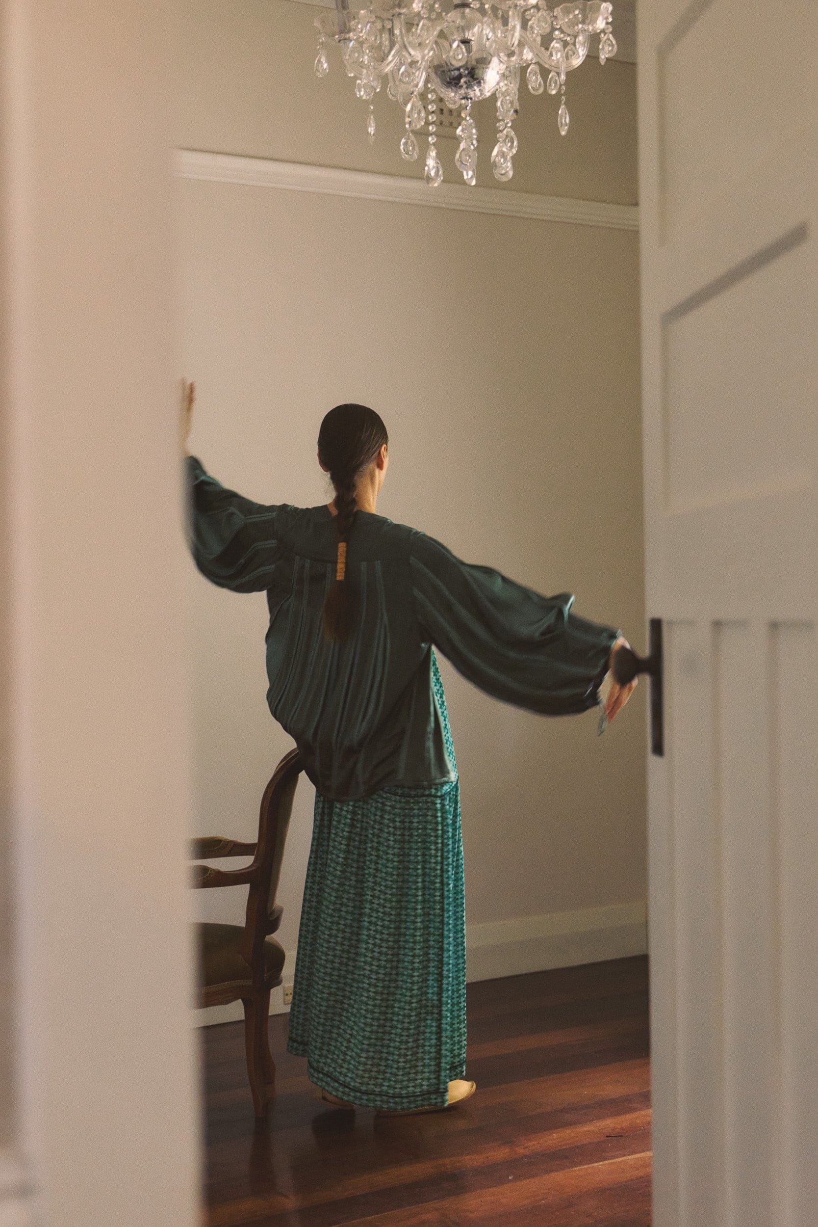 Model wearing green box pleat jacket & green patterned dress, campaign image