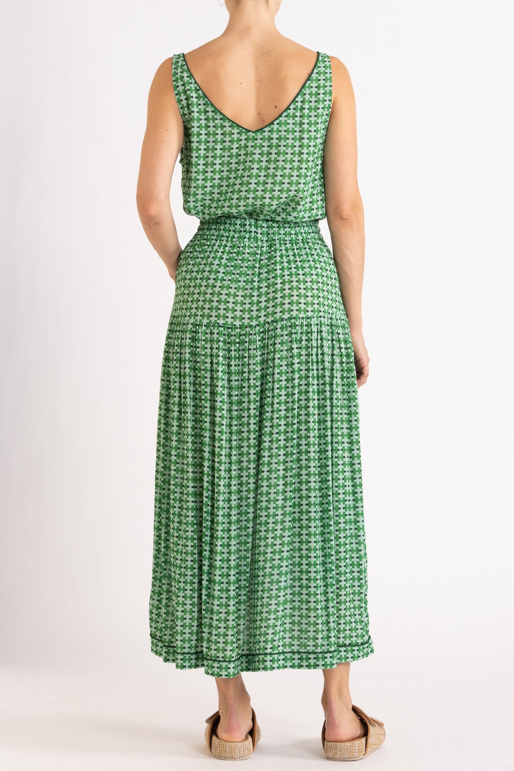 Model wearing green patterned tank and skirt, back view