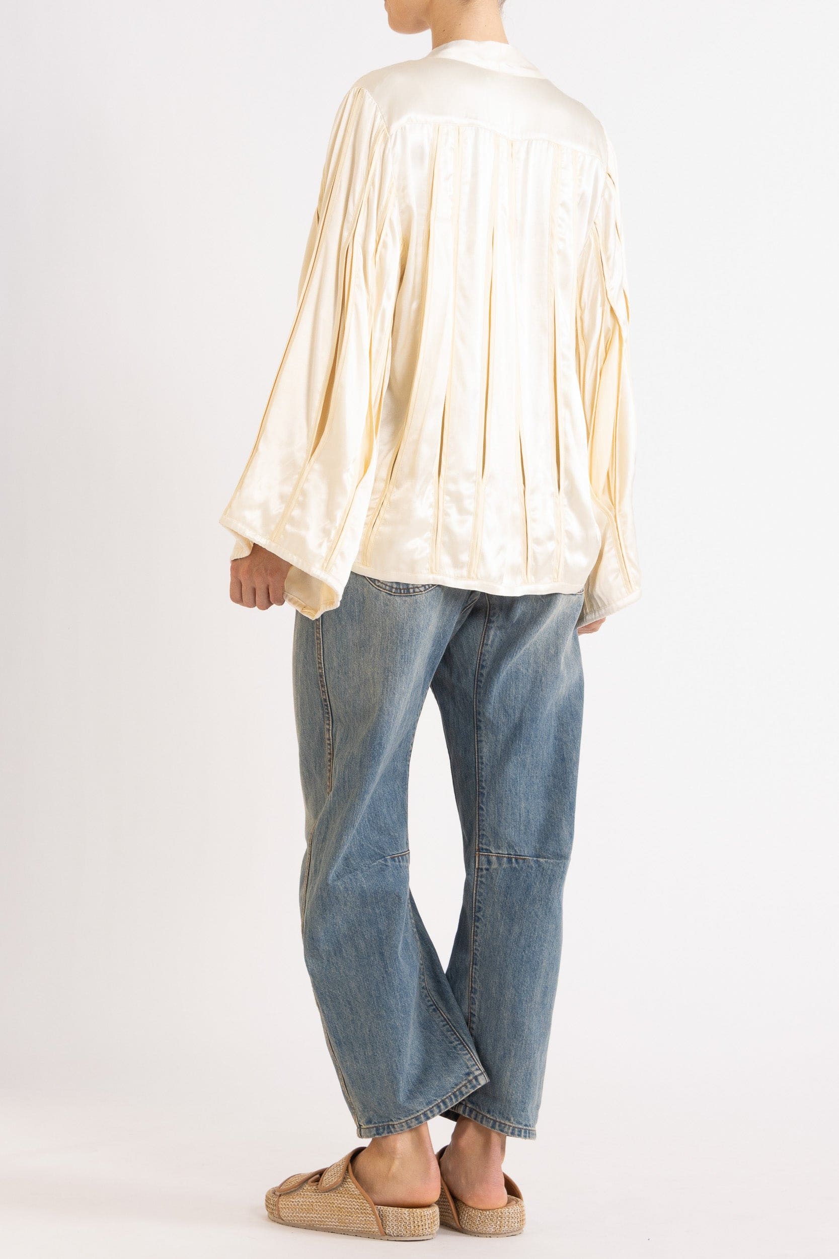 Model wearing cream box pleat jacket, white lace camisole & denim jean, back-side view