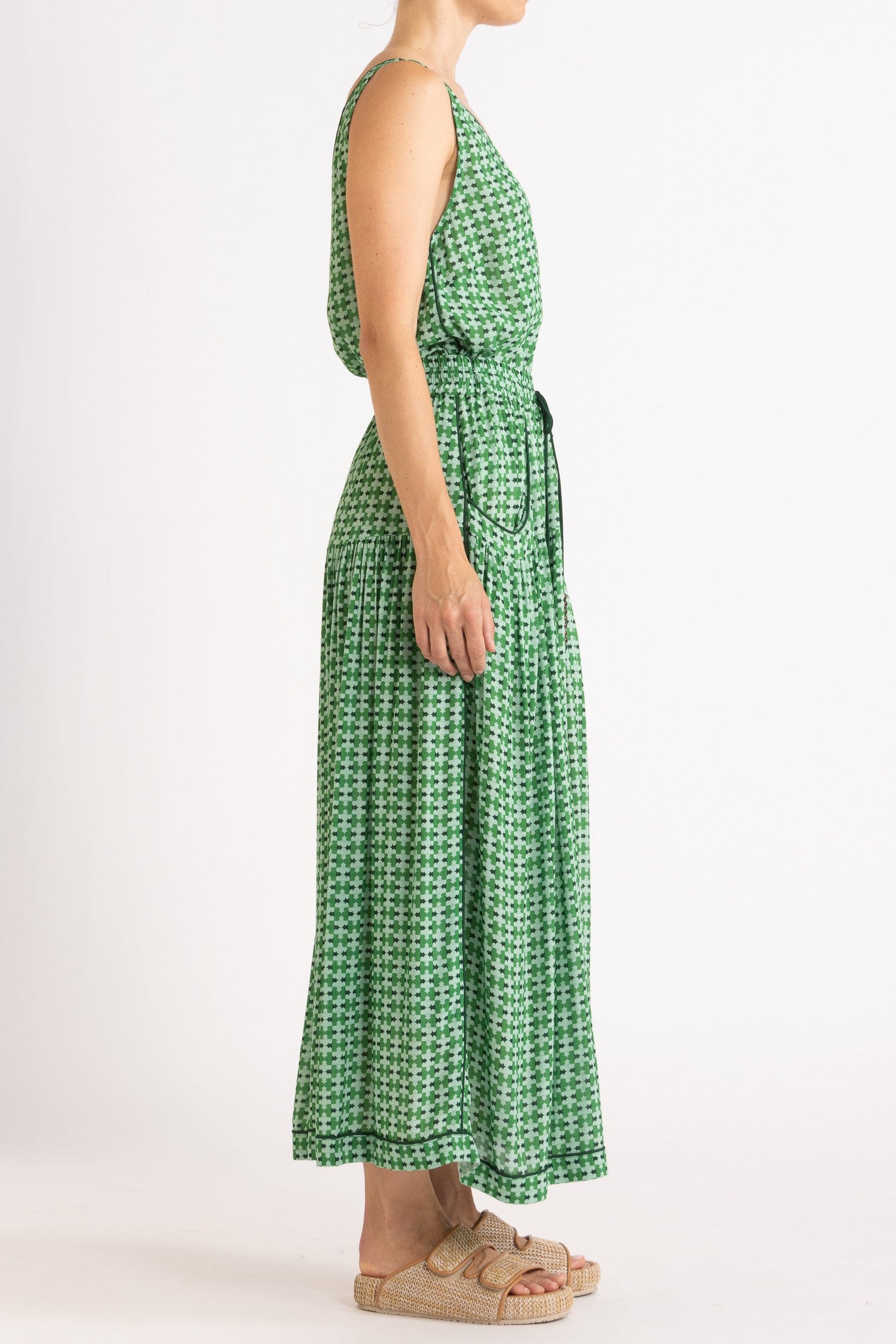 Model wearing green patterned tank and skirt, side view