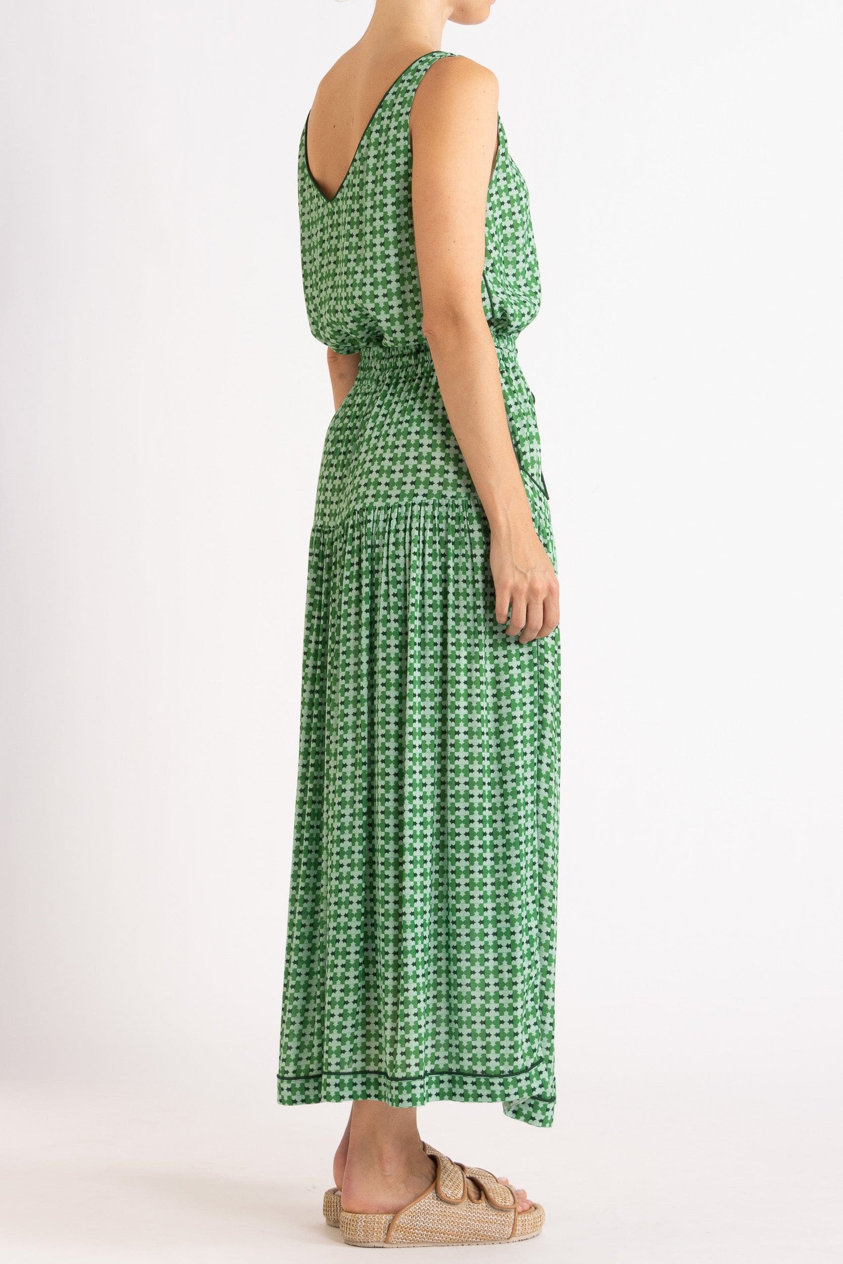 Model wearing green patterned tank and skirt, side-back view