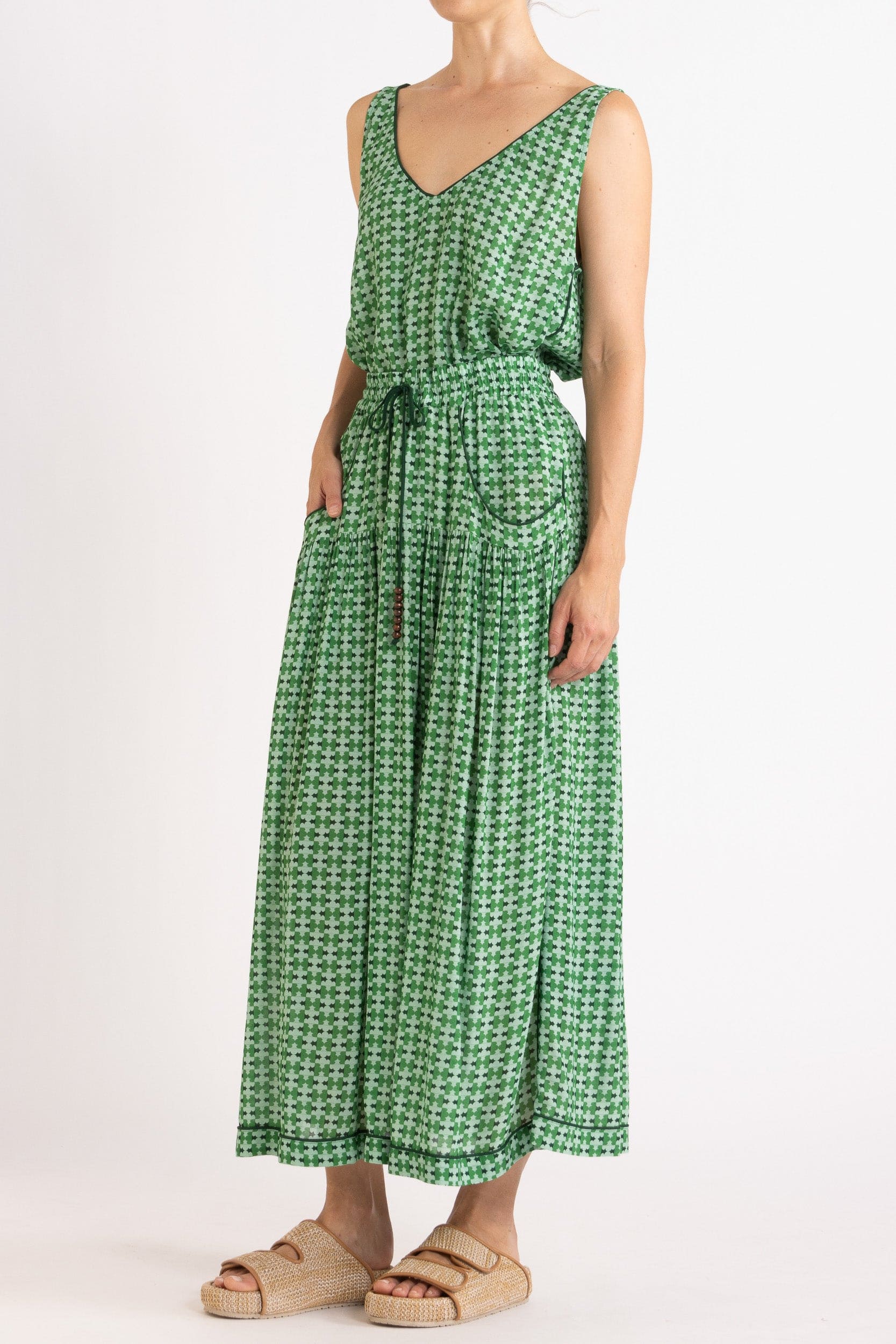 Model wearing green patterned tank and skirt, front-side view