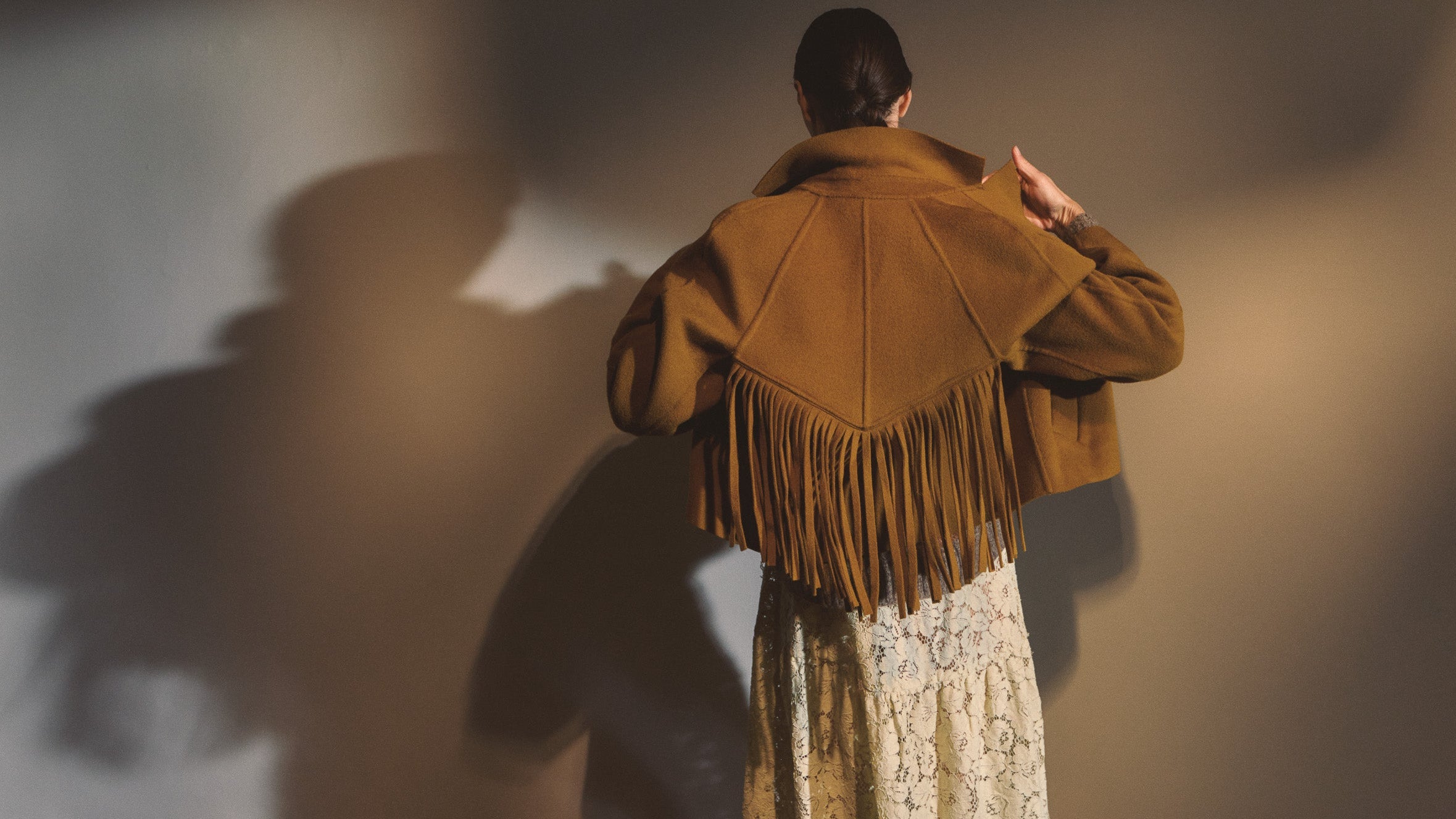 model wearing brown fringed jacket & green-tea lace dress