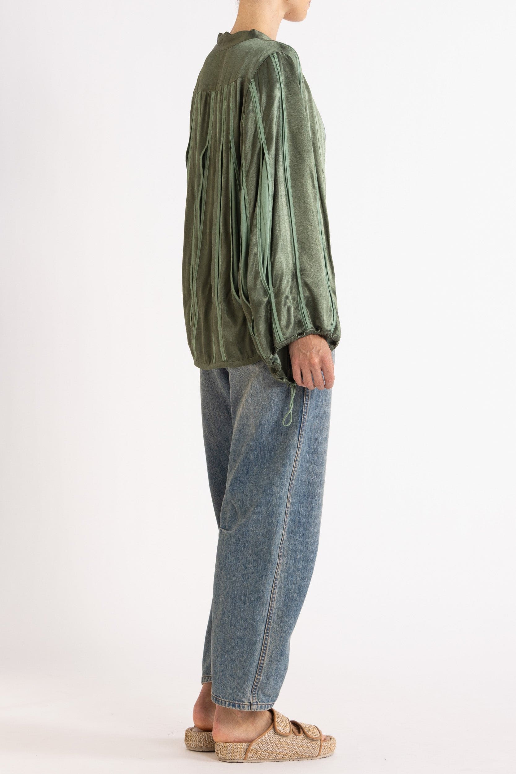 Model wearing green box pleat jacket, blue lace camisole & denim jean, side-back view