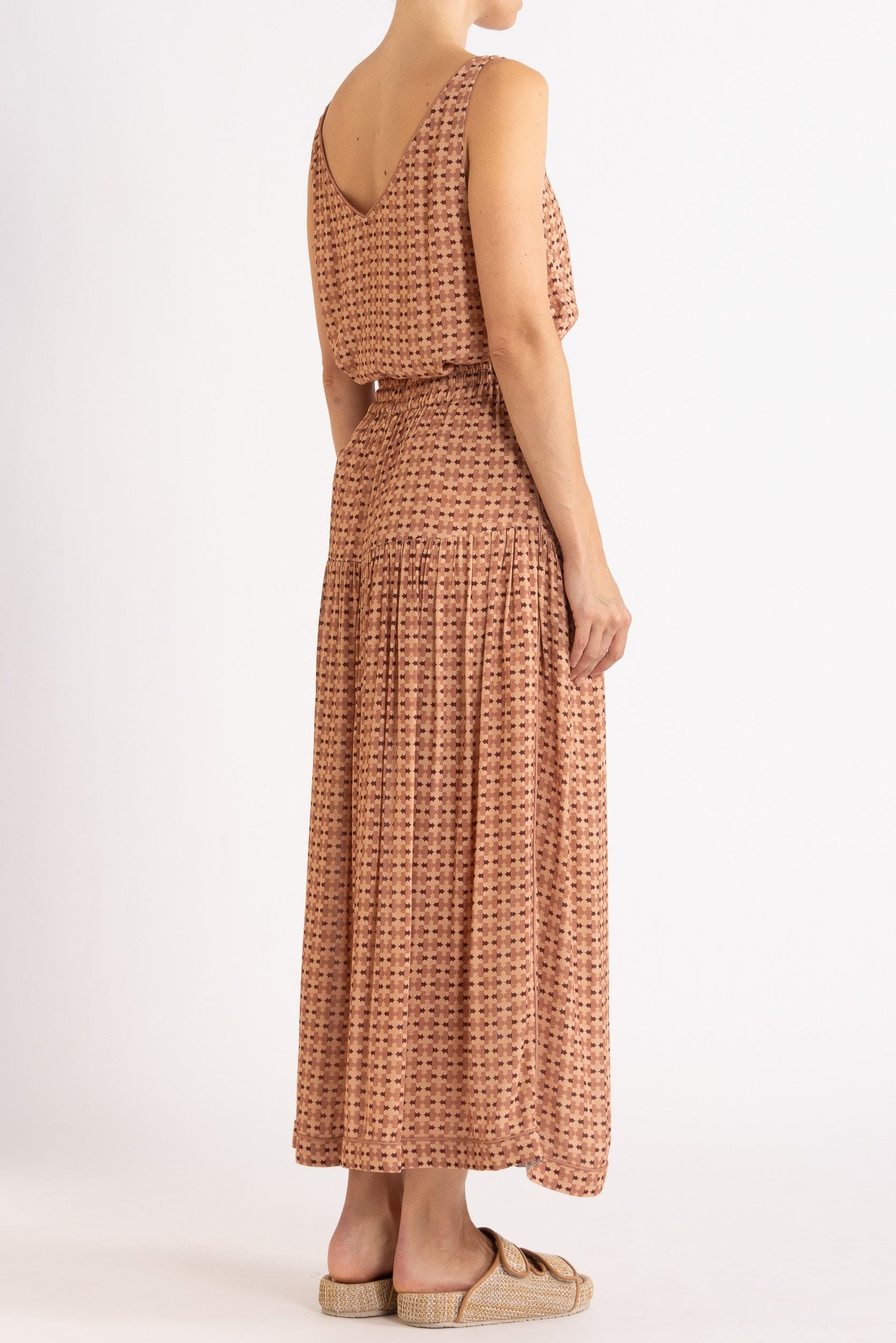 Model wearing peach patterned tank and skirt, side-back view