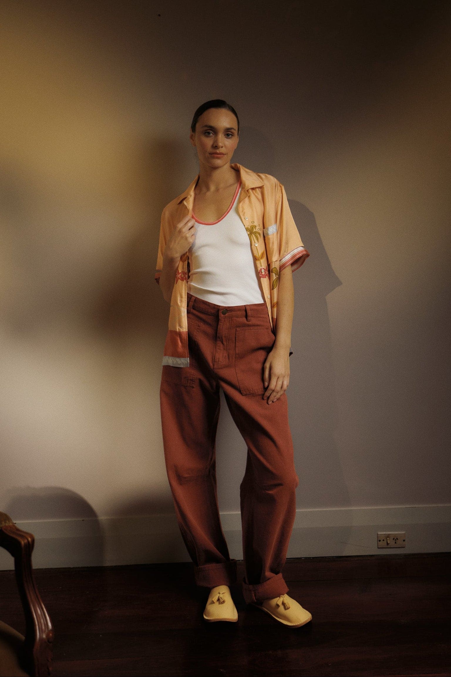 Model wearing a peach vacation-style print shirt, white ribbed singlet and pinot-coloured cotton-twill pant, campaign image
