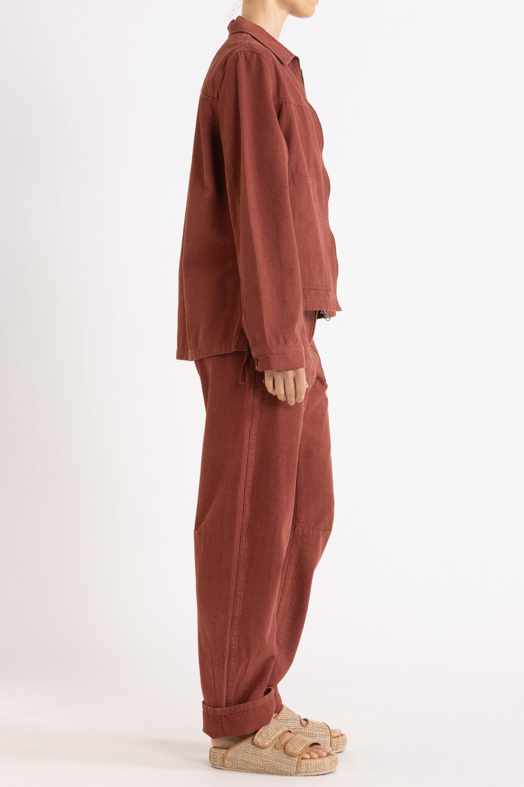 Model wearing burgundy cotton-twill utility jacket & pant, side view